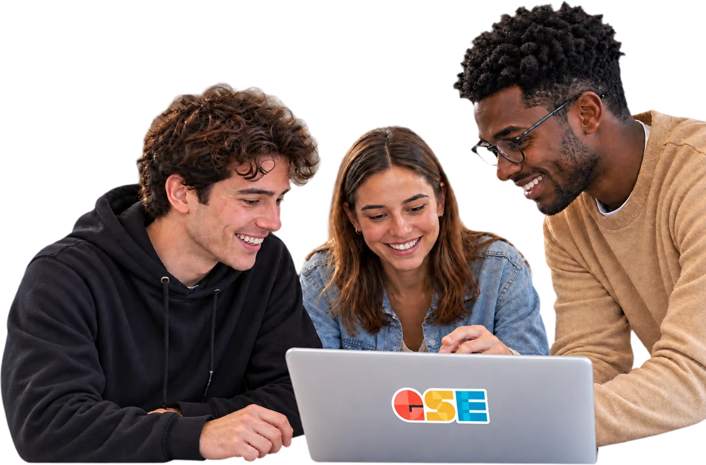 Three students smiling together around a laptop.