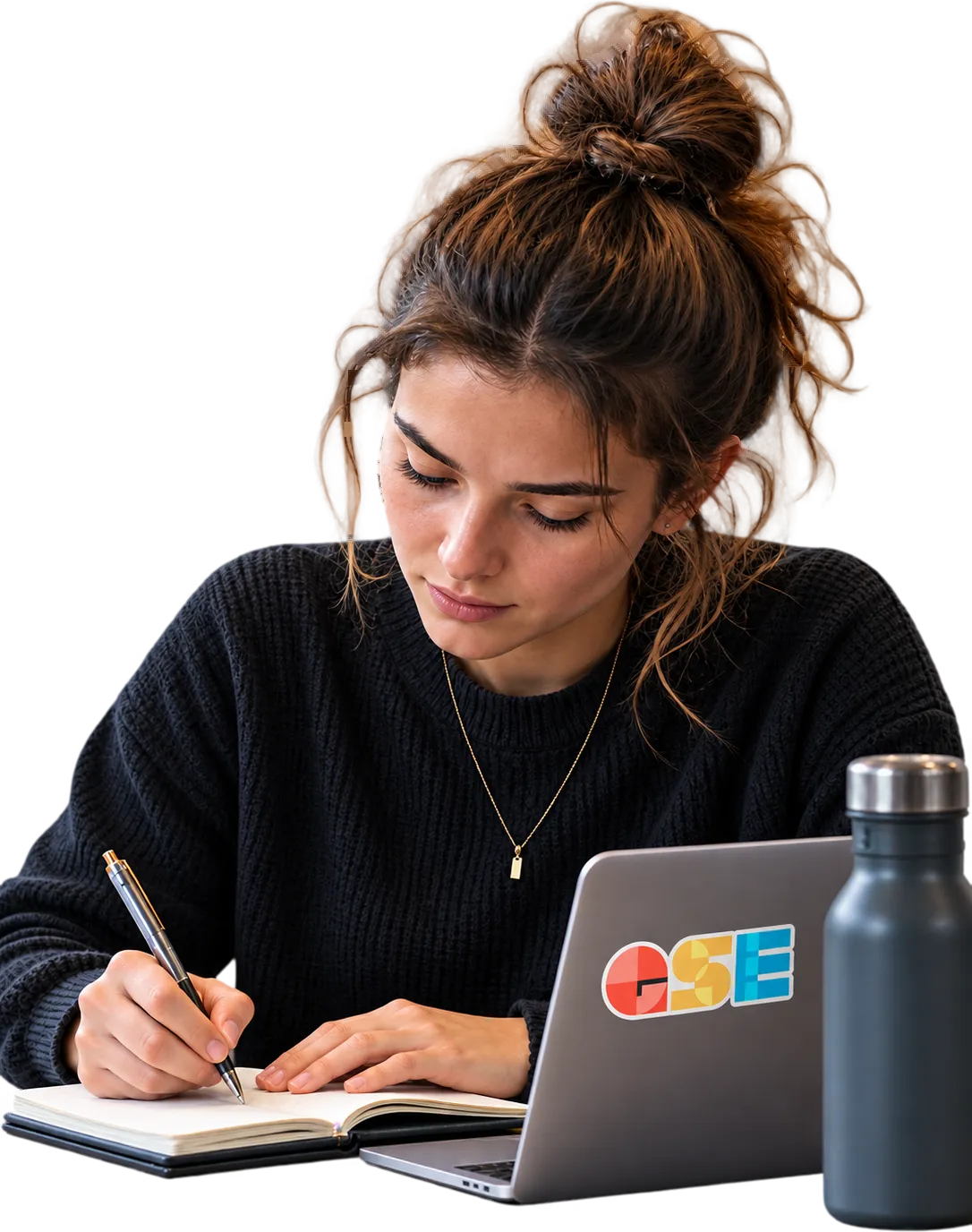 A student taking notes next to a laptop.